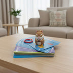 A children's early education card game set with a light blue box a small squirrel toy, a stack of colorful cards, and a red ring, arranged on a white surface with decorative leaves and flowers in the background.
